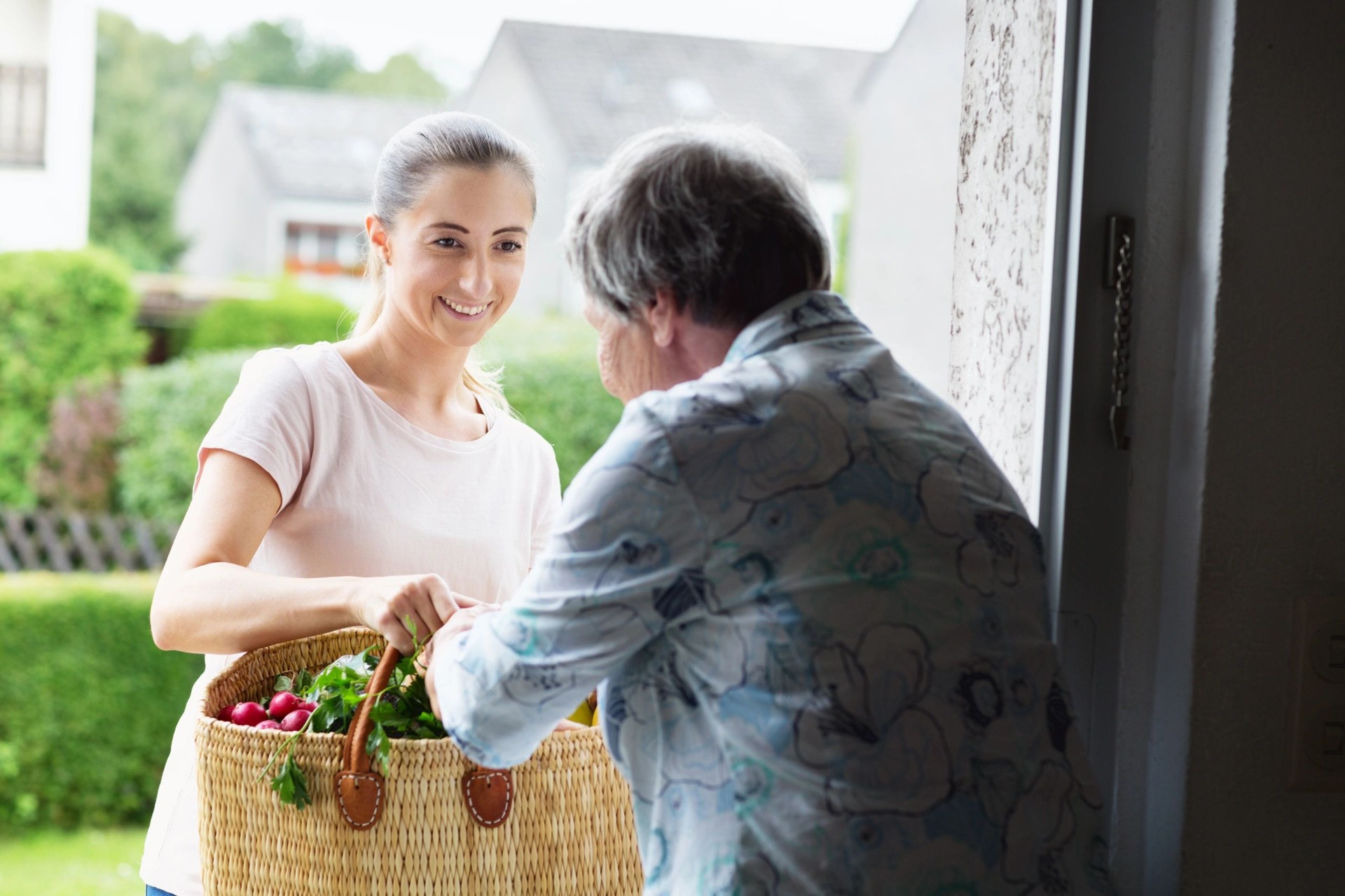 Volunteer delivering a basket of groceries to a senior at her front door