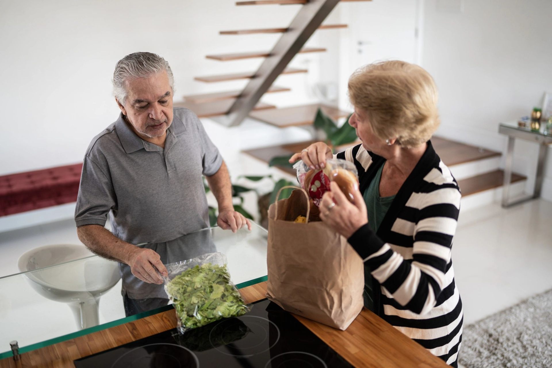 Seniors unpacking groceries together in their kitchen