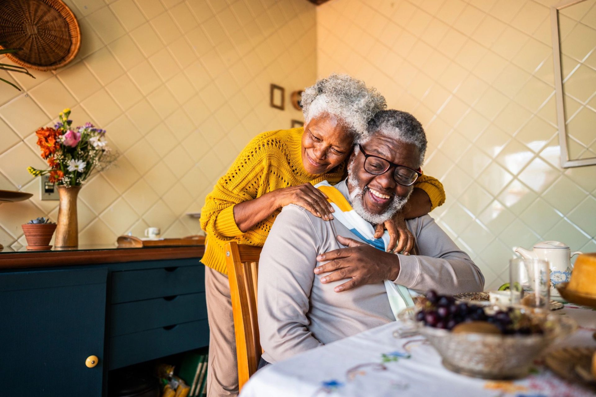 A senior couple sharing a warm embrace at the kitchen table